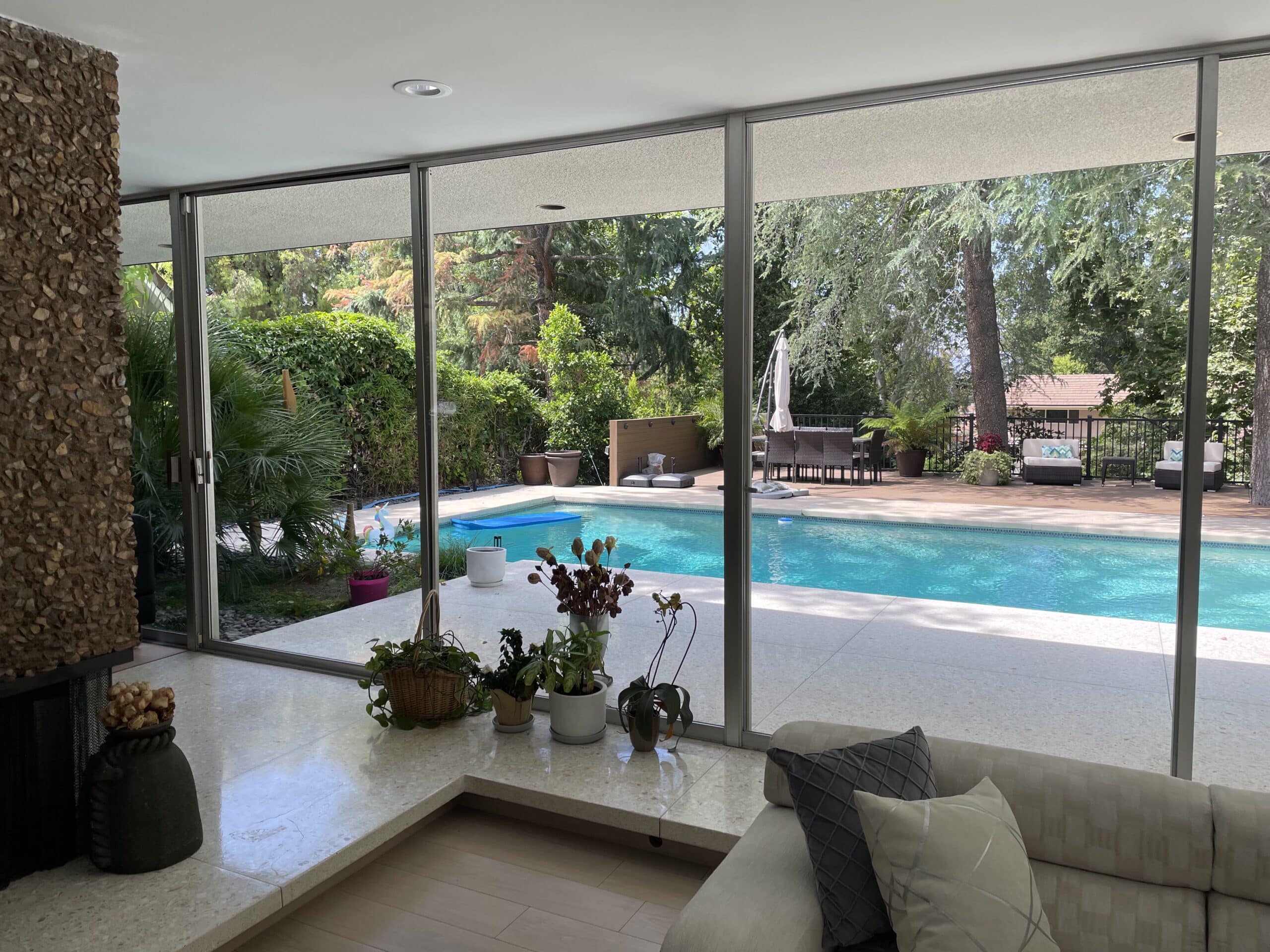 Clean floor-to-ceiling windows overlooking a swimming pool and garden
